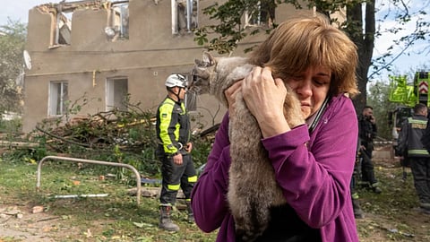 A woman holds her cat after it being found during search and rescue works in the damaged residential building following Russia's missile attack in Kharkiv, Ukraine